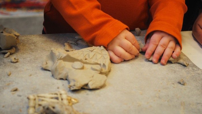 Barnhänder som knådar lera