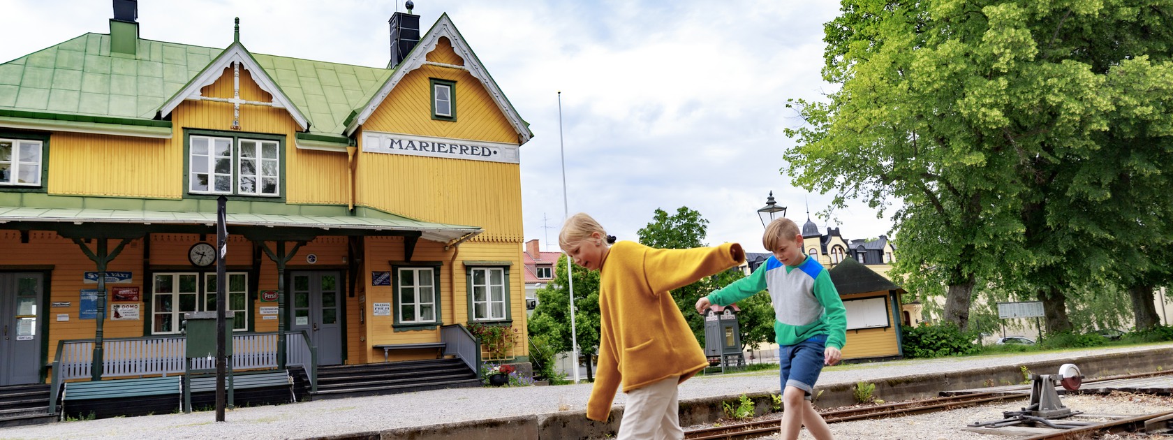 Två barn som balanserar på ett järnvägsspår i Mariefred museijärnvägen.